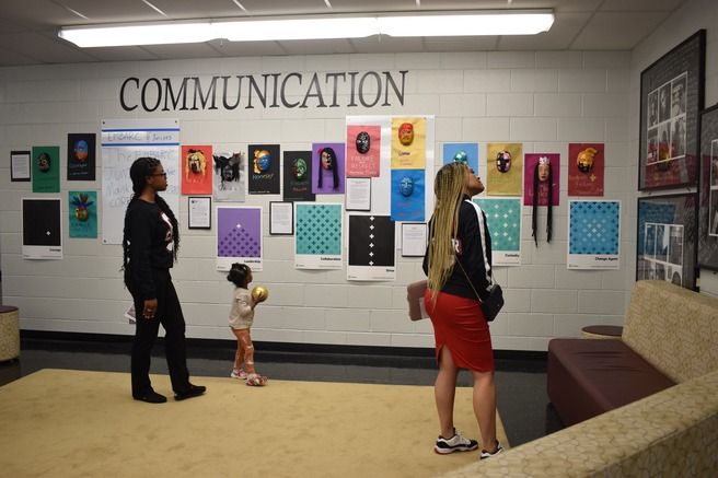 a group of people looking at posters on a wall